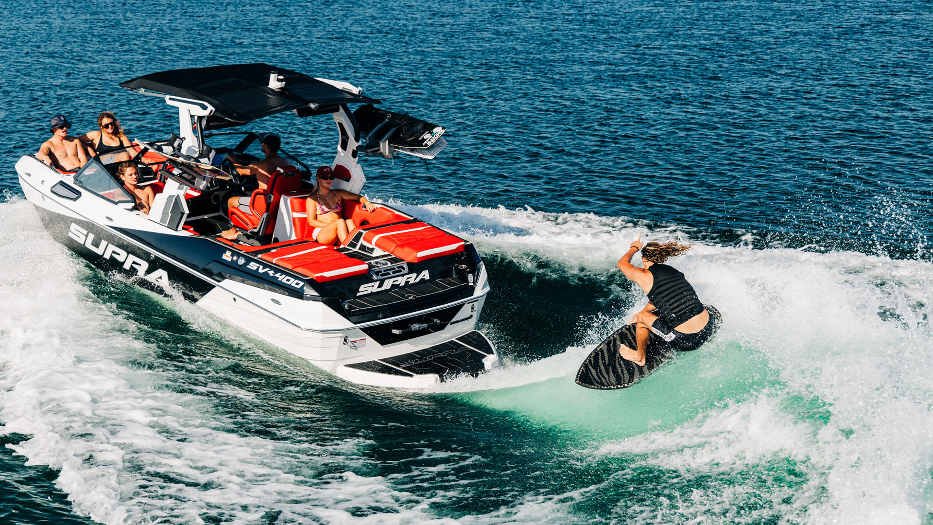 wake surfer behind Supra boat with happy passengers